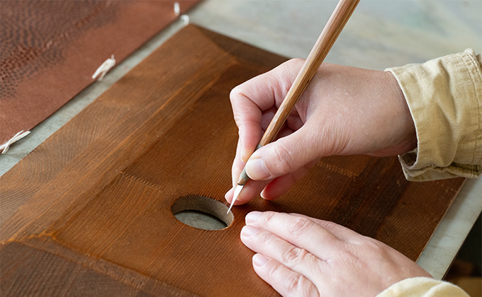⑥「突彫」は、細い刃が折れないように穴板と呼ばれる板を使い、穴板の上で渋紙を動かしながら彫っていく